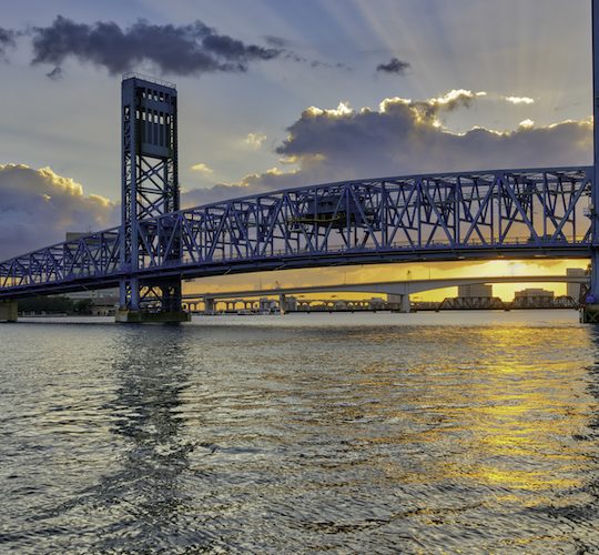 a bridge over water with a sunset in the background at The Vista Bay