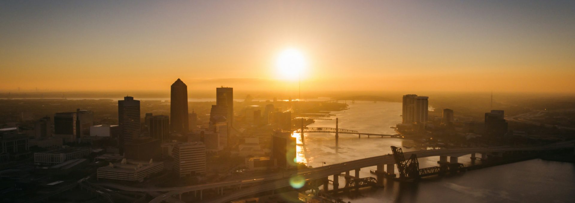 aerial photography of bridge and building beside river during sunset