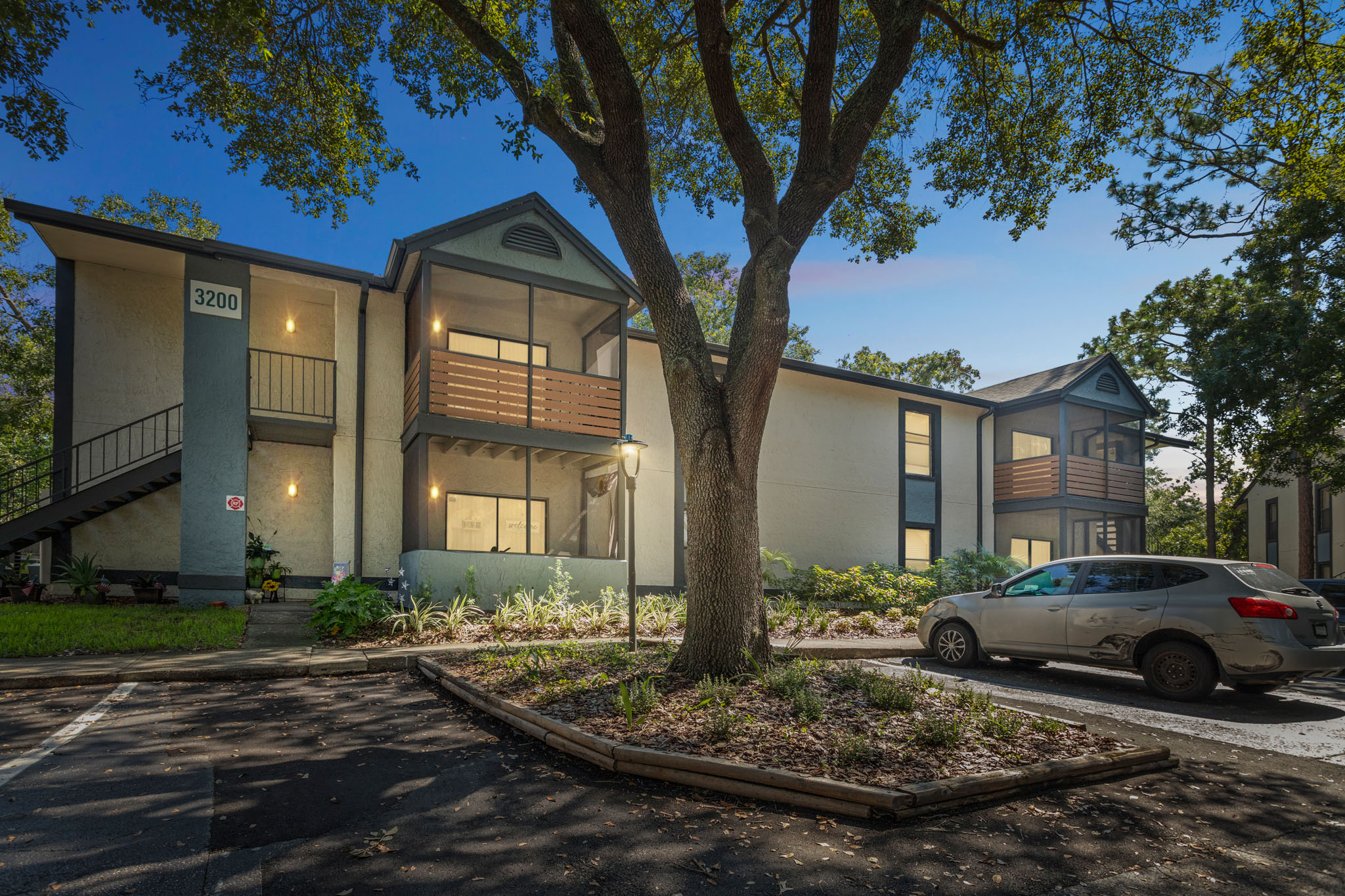 the exterior of an apartment complex with trees and cars parked in front at The Vista Bay