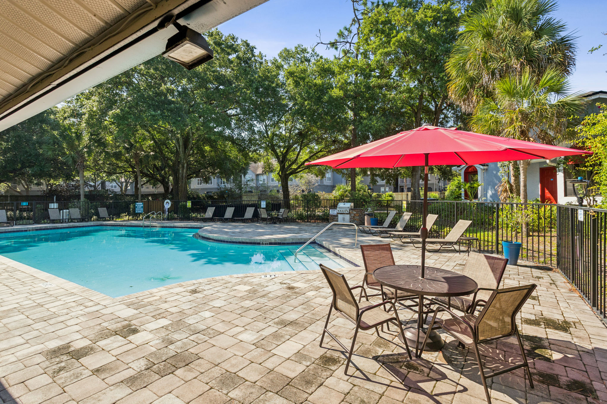 a patio with a pool and umbrella and chairs at The Vista Bay